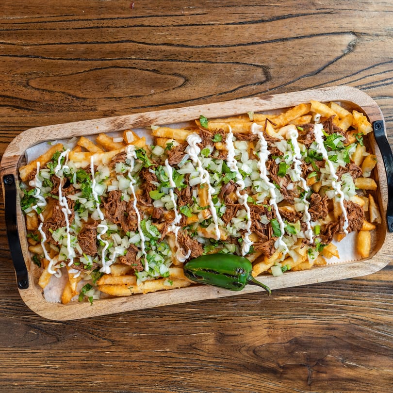 Mexican Mariachi Grill's carne asada fries, topped with shredded beef, onions, cilantro, and crema.
