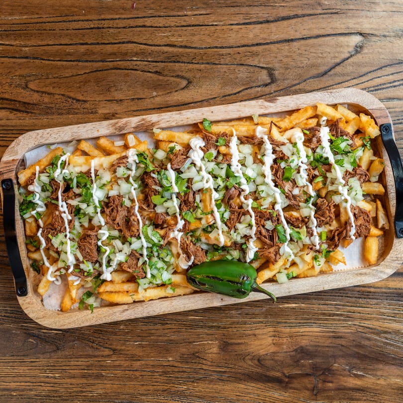 Mexican Mariachi Grill's loaded fries with shredded meat, onions, cilantro, crema, and a jalapeño.